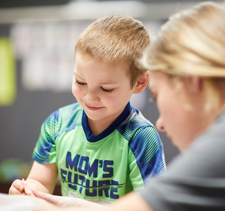 A young student concentrating on classwork with a teacher